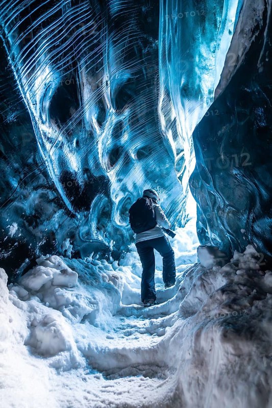 A person is walking through a cave with blue walls. The cave is very cold and the person is wearing a jacket