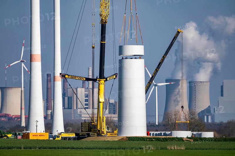 Construction site of the new Bedburg 3 wind farm, on recultivated open-cast mining site, 9 wind power plants with an output of 60 megawatts are newly built, installation of the wind turbine tower, in the background the Neurath lignite power plant, operated by RWE and the city of Bedburg, North Rhine-Westphalia, Germany