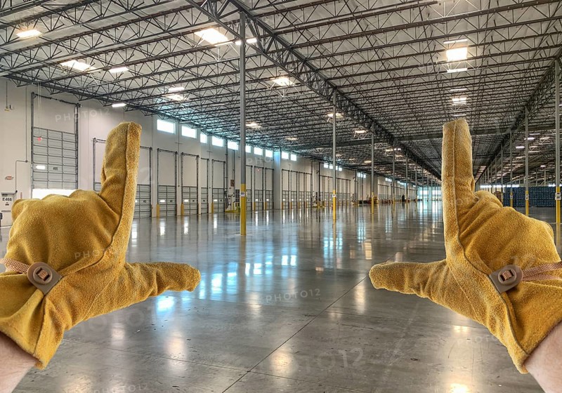 Framing Hands Wearing Leather Construction Gloves in Empty Industrial Warehouse