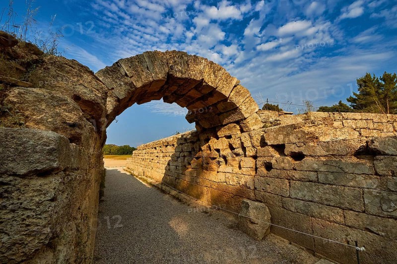 Crypt, vaulted entrance to the stadium, ancient stone arch with distinctive shadows along old walls under a clear sky, archaeological site, Ancient Olympia, Olympia, Peloponnese, Greece