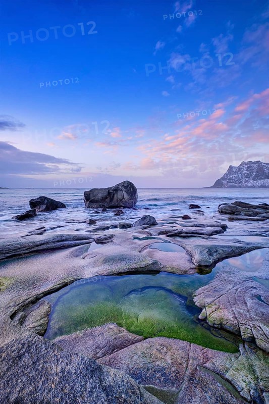 Rocks on beach of fjord of Norwegian sea in winteron sunset. Utakliev beach, Lofoten islands, Norway