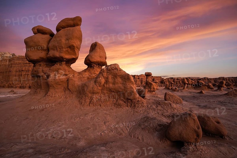 Dramatic sandstone formations under a vibrant sunset sky at Goblin Valley State Park, Utah. Captures the unique erosion and stunning colors of this natural landscape