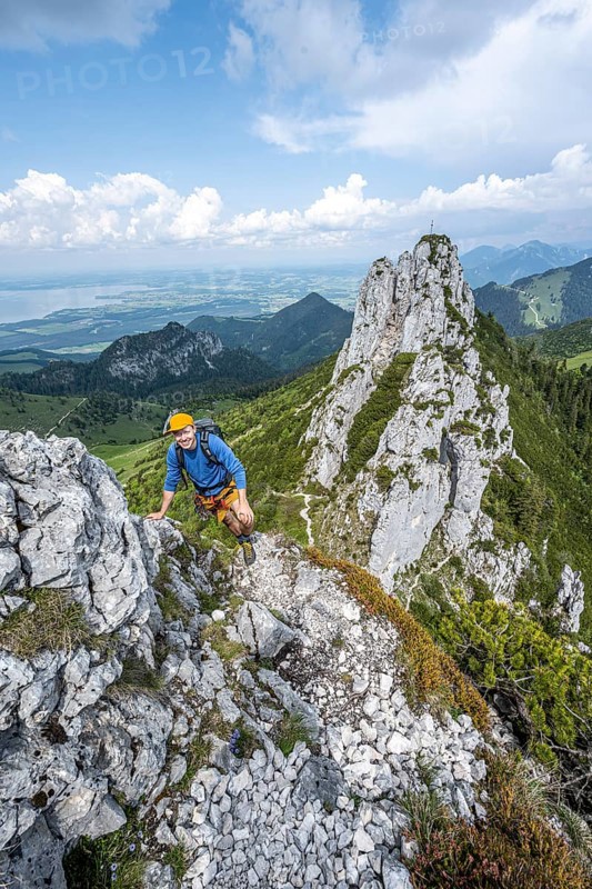 Climber on a climbing tour, on a mountain ridge, behind the summit of the Kampenwand with summit cross, alpine climbing, crossing the Kampenwand, Chiemgau, Bavaria, Germany