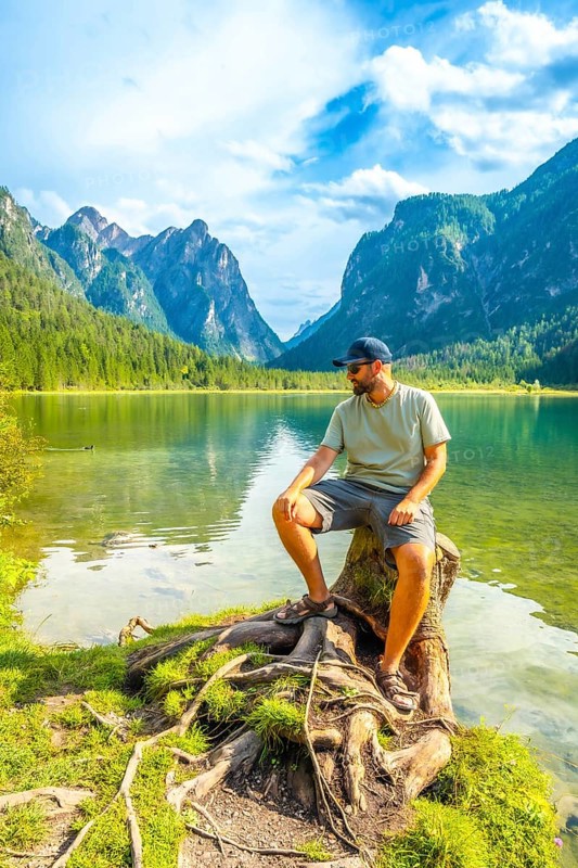 Tourist enjoying the breathtaking view of lake dobbiaco and the dolomites on a sunny summer day