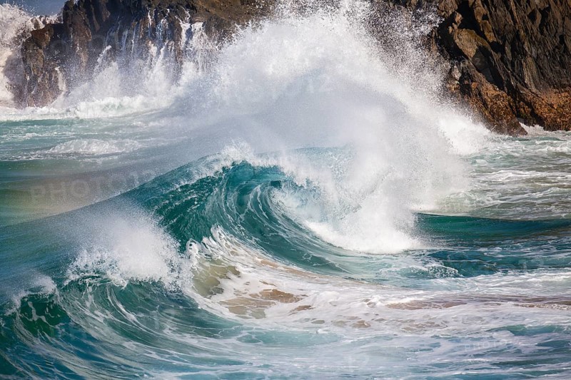 Waves crash against rocks at the mainland's easternmost point, creating rainbows in the ocean spray. Daylight, Byron Bay, New South Wales, Australia