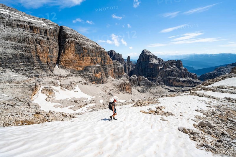 Mountaineers in a snowfield on the Sella della Tosa, mountain landscape with steep cliffs, Brenta Mountains, Brenta-Adamello Natural Park, Trentino, Italy