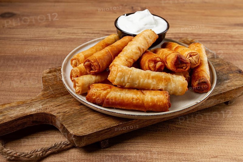 Fried spring rolls with cheese, on a wooden background, with cream sauce, no people
