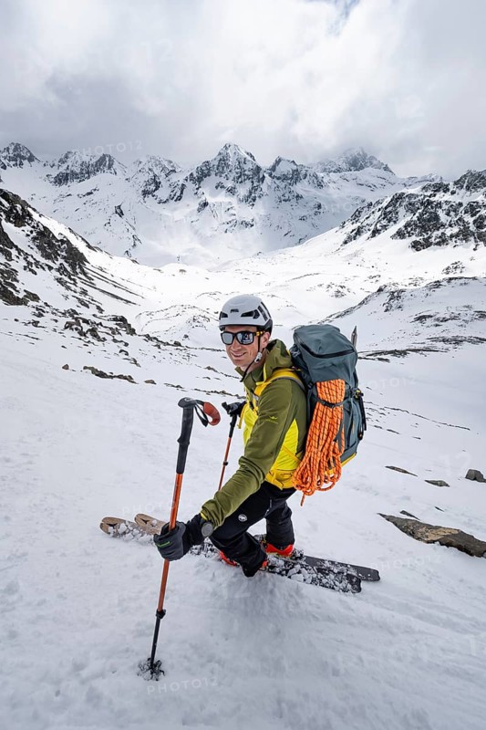 Skier skiing down a steep slope, Piz Laviner, view of mountain panorama in wintry mountain landscape with dramatic clouds, Grisons Haute Route, Albula Alps, Rhaetian Alps, Grisons, Eastern Switzerland, Switzerland