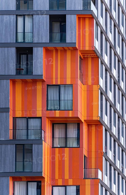Detail of modern architecture blending glass, concrete, and metal in a suburb high-rise building, showing orange and gray exteriors