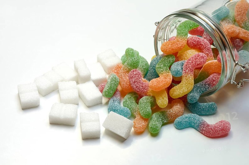 Lots of colorful jelly sweets in glass containers and sugar cubes, sugar consumption