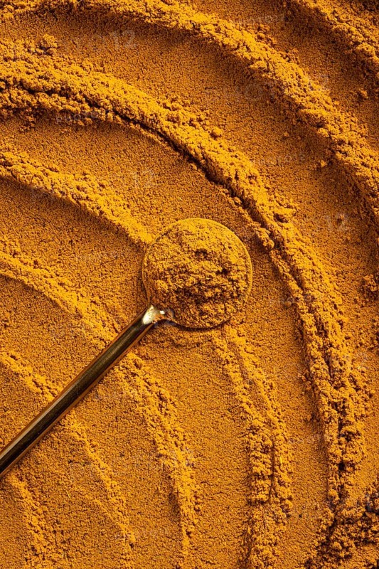 A vibrant close-up of golden curry powder, showcasing its textured surface with swirling patterns This aromatic spice is perfect as an ingredient for cauliflower curry soup and more