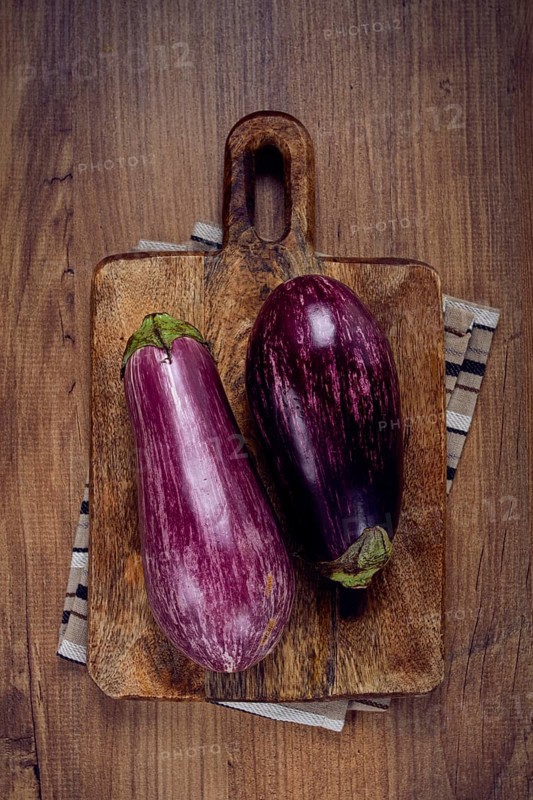 Purple and white eggplant, on a wooden chopping board, top view, raw eggplant, no people