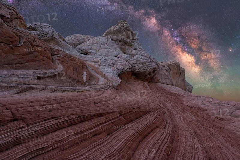 Stunning nightscape of White Pocket in Arizona showcases the Milky Way galaxy arching over unique desert rock formations, creating a breathtaking celestial view