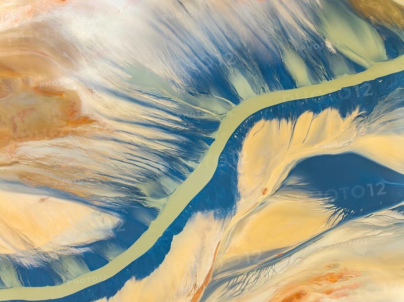 From above, this striking aerial shot captures vibrant natural textures and a sinuous river amidst earthy tones. The image, perfect for backgrounds or thematic designs, showcases the beauty and complexity of abstract landscapes