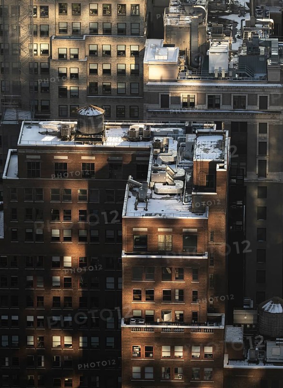 Top view of a New York City block capturing buildings bathed in the golden light of sunset, highlighting textures and rooftop details