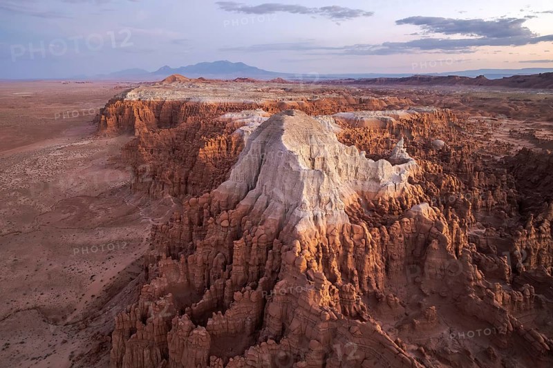 Captivating aerial shot of Goblin Valley State Park in Utah, showcasing its intricate landscape and towering rock formations under a fading sunset, creating a surreal, otherworldly panorama