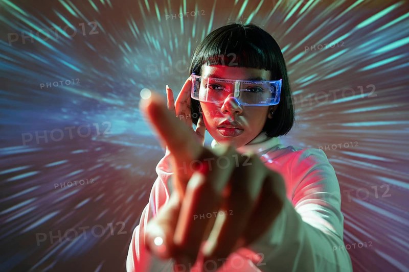 Latin woman interacts with an immersive virtual reality environment, wearing VR glasses. The scene is vibrant with colorful lights, symbolizing futuristic technology and digital innovation