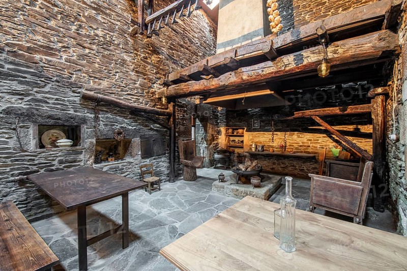 Traditional stone-walled kitchen inside an old country house in Lugo, Spain, featuring wooden beams, vintage furniture, and rural decor
