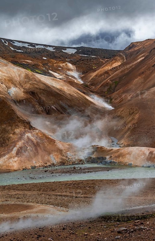 Steaming stream between colourful rhyolite mountains with snowfields, Hveradalir geothermal area, Kerlingarfjöll, Icelandic highlands, Iceland