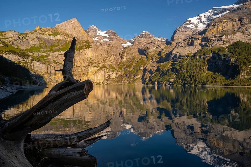 A breathtaking view of Oachinensee in Switzerland, showcasing mountains mirrored in the tranquil lake. The serene atmosphere and rugged landscape captivate the essence of nature