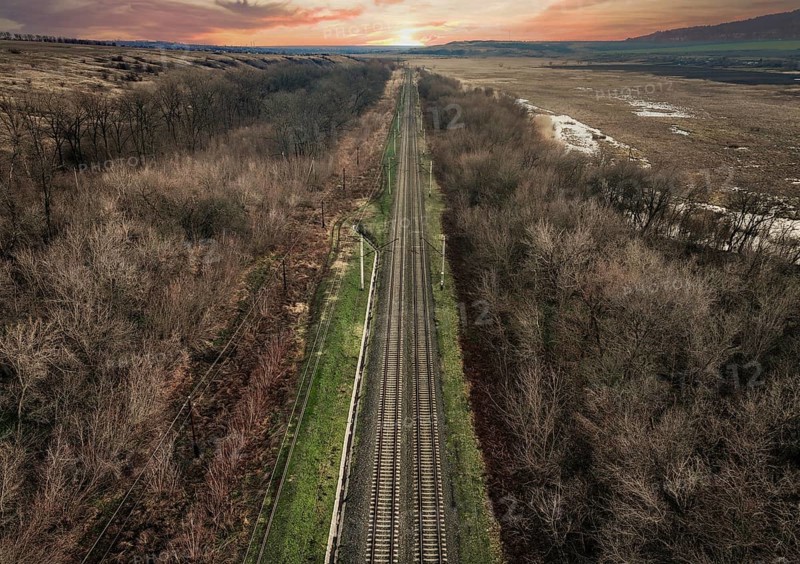 From above, a drone captures the serene landscape of a railway slicing through a barren forest in Ukraine, showcasing the contrast between the man made structure and the natural surroundings at sunset