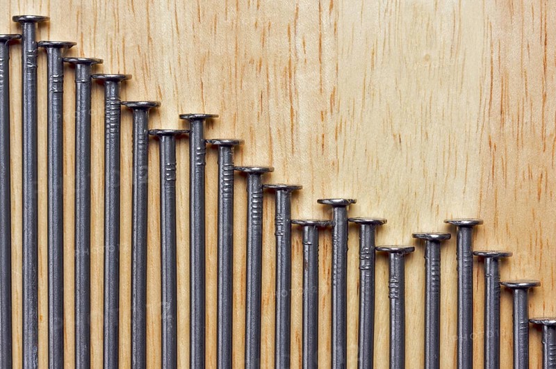 Declining Graph of Nails on a Wood Background