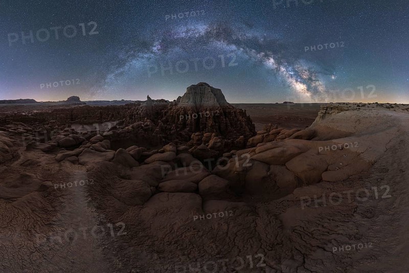 A breathtaking panorama of the Milky Way arcing over the uniquely eroded rock formations of Goblin Valley State Park in Utah, captured in a serene desert landscape at nighty with the natural sculptures of the park