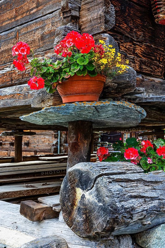 Flower-decorated barn on wooden supports and stone slabs, historic village centre, Grimentz, Val d'Anniviers, Valais Alps, Canton Valais, Switzerland