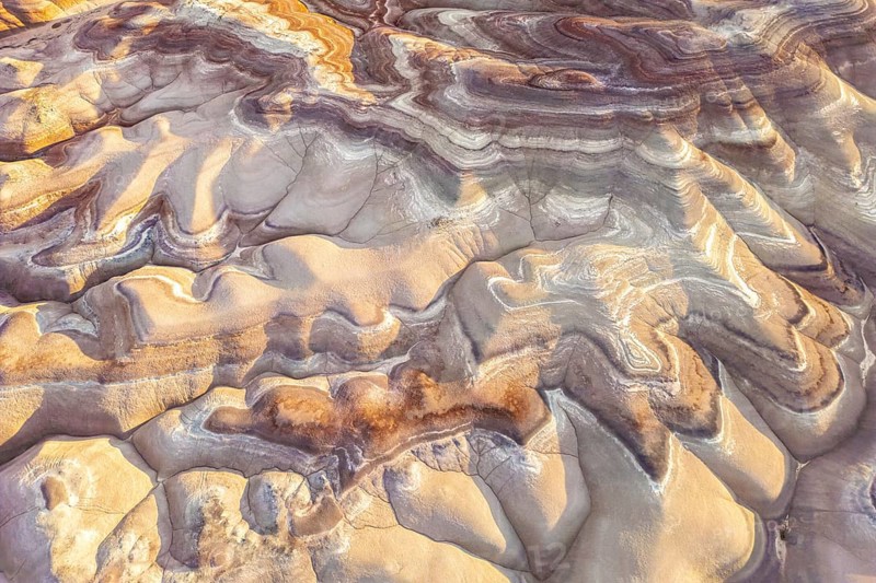 Aerial view of golden bentonite formations in Utah, USA, showcasing stunning earth patterns and textures. The natural hues create captivating visual interest