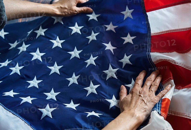 Hands gently hold the American flag, with its iconic stars and stripes. This image symbolizes patriotism, unity, and pride, capturing the essence of national identity and respect