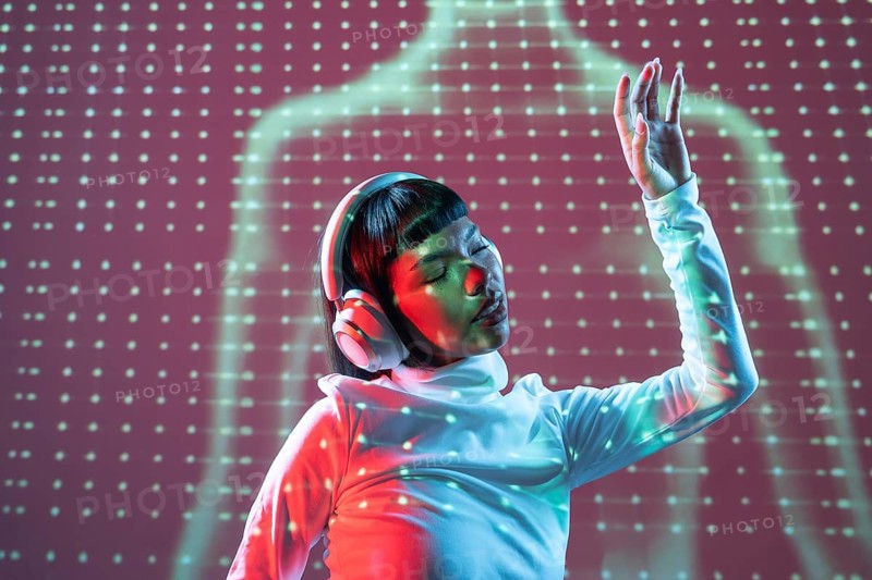 A futuristic Latin woman enjoys music through headphones. Immersed in the sound, her expression reflects a deep connection, set against a vibrant, tech-inspired background