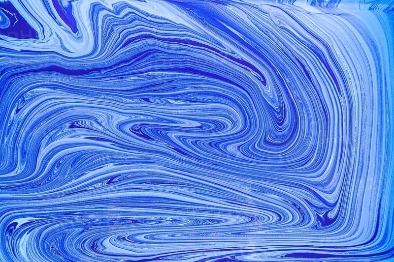 This image showcases a pattern of blue and white acrylic paint swirls resembling marble. The fluid, abstract design creates a sense of motion and elegance, perfect for artistic projects