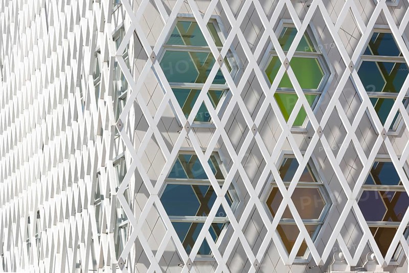 Abstract view of a auditorium facade showcasing geometric patterns of interlocking diamond shapes and hexagonal windows. The modern design highlights symmetry and innovation