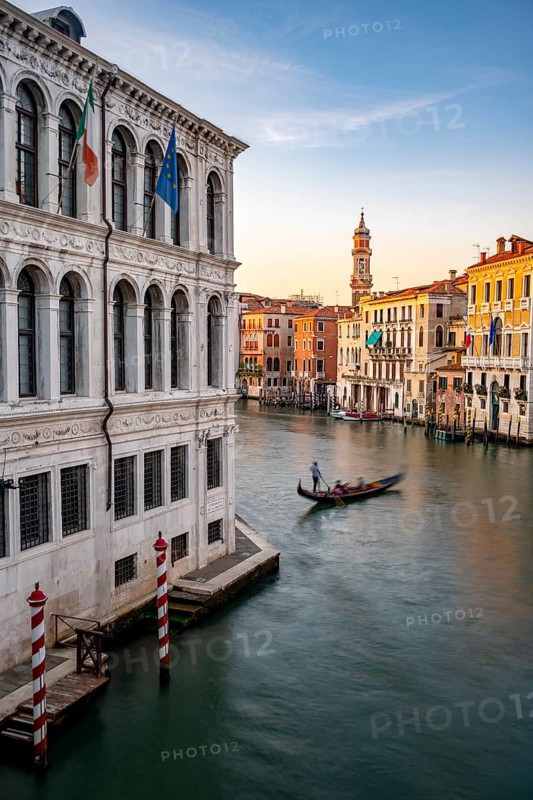 View of the Grand Canal with gondoliers at sunset, picturesque evening mood with palazzos on the canal and church tower of the Chiesa Parrocchiale dei Santi Apostoli, long exposure, view from the Rialto Bridge, Venice, Veneto, Italy