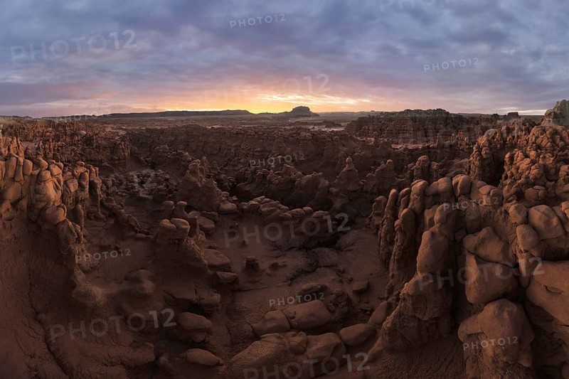 A panoramic aerial photograph capturing the unique rock formations and vast landscape of Goblin Valley State Park, Utah, during sunset