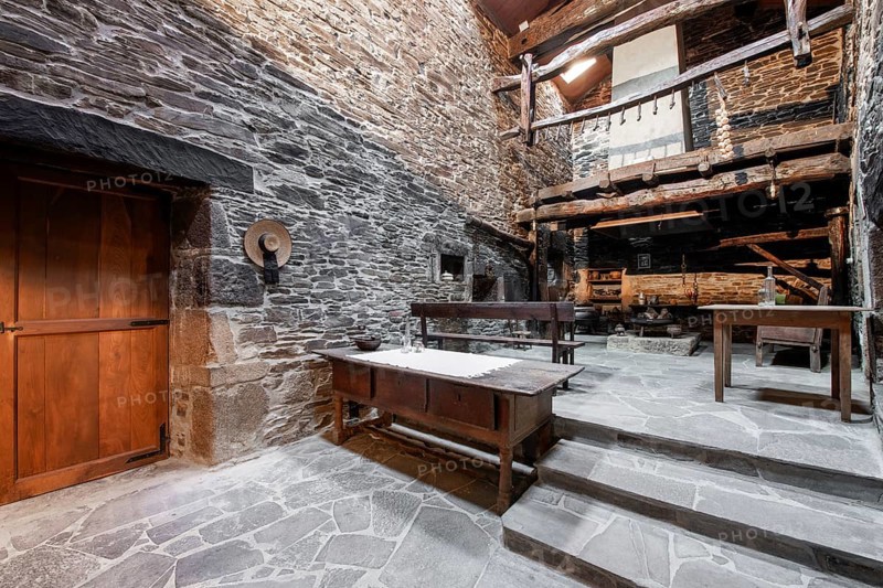 An authentic rustic kitchen featuring stone walls and wooden beams in a historical country house in Lugo, Spain, with vintage furniture and traditional decor