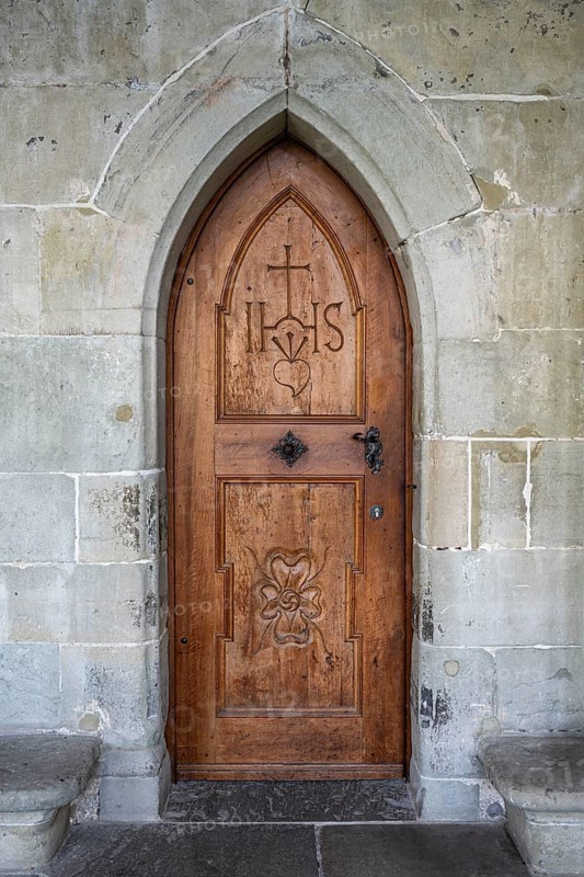 Wooden door with carvings and religious symbols in stone arch, Gothic architecture in the cloister of Constance Cathedral, traditional craftsmanship, Constance, district of Constance, Baden-Württemberg, Germany
