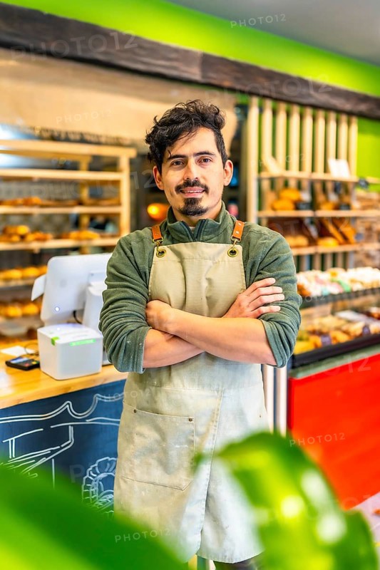 Vertical portrait of a latin male artisan baker standing proud in the shop of new business