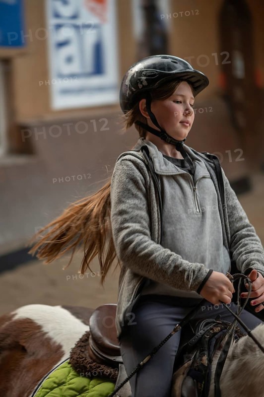 Little girl, 10 years old, in the saddle on a horse in an indoor riding arena, Mecklenburg-Vorpommern, Germany