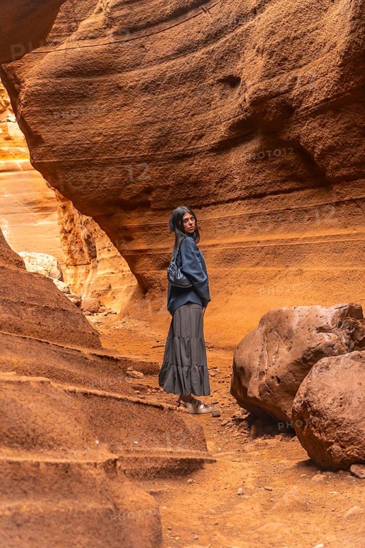 Tourist walking through the unique rock formations of barranco de las vacas, a stunning canyon in gran canaria, spain, enjoying the beauty of nature