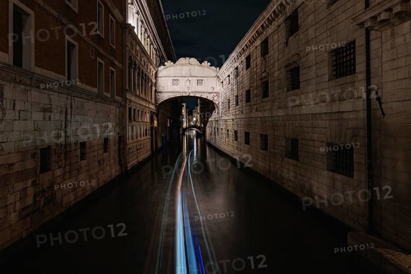 Serene nighttime beauty of Venice, Italy, with its stunning historic architecture gracefully illuminated above a tranquil canal, capturing the city enchanting allure