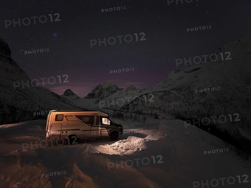 Winter motorhome under a starry sky on the island of Senja in a serpentine, Troms, Norway