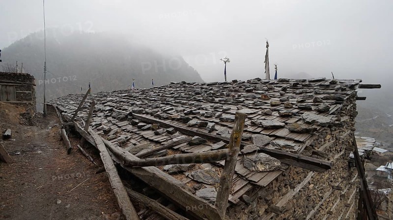 Stone roof of an old building in a foggy mountain village, trekking at Annapurna Circuit, Manang, Nepal