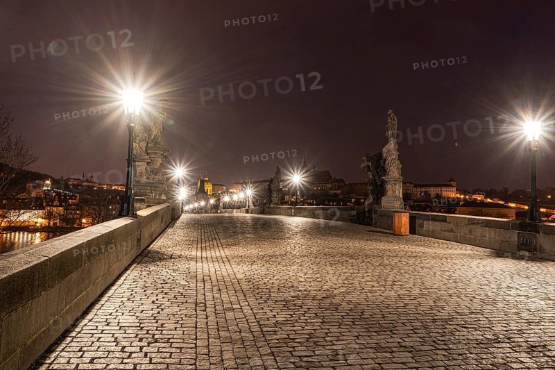 Illuminated at night, Charles Bridge in Prague showcases statues and cobblestones under glowing streetlights, reflecting Old Prague's architectural beauty and history