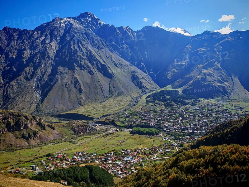 Panorama of a valley with a city and dramatic mountain ranges, Stepantsminda, Caucasus, Georgia