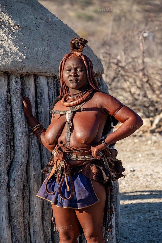 Married Himba woman leaning against a traditional mud house, traditional Himba village, Kaokoveld, Kunene, Namibia