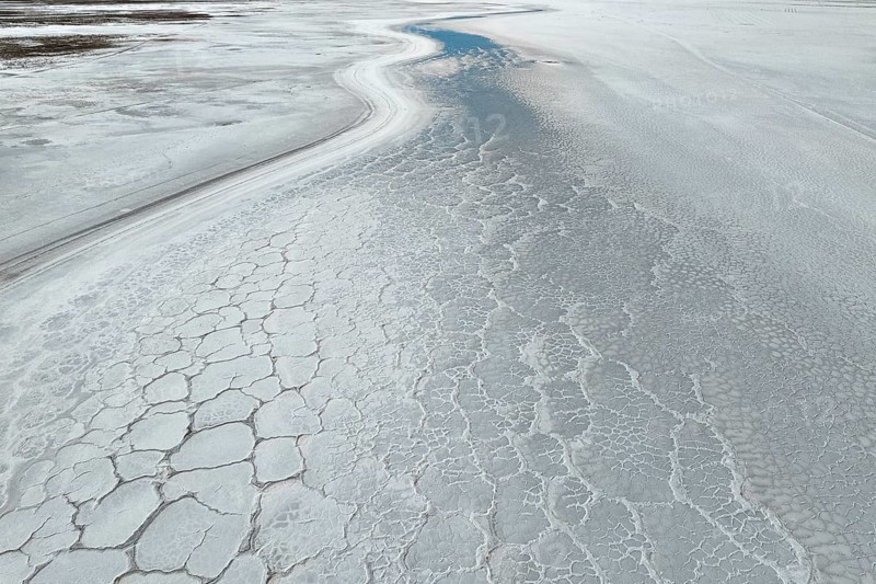 A mesmerizing aerial view of a saline mud landscape, showcasing intricate natural patterns and textures in earthy hues. The serene, cracked surface adds a unique visual appeal