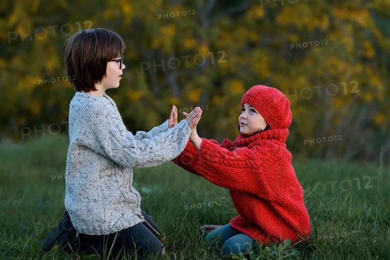 A boy and a girl enjoying a playful moment together in a vibrant autumn park setting, surrounded by yellowing trees and crisp, fall air