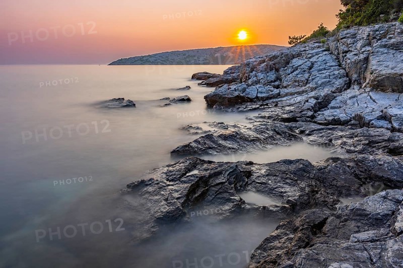 Sunset over crystal clear water on the beach of Ustrine Bay on the island of Cres, long exposure, Croatia