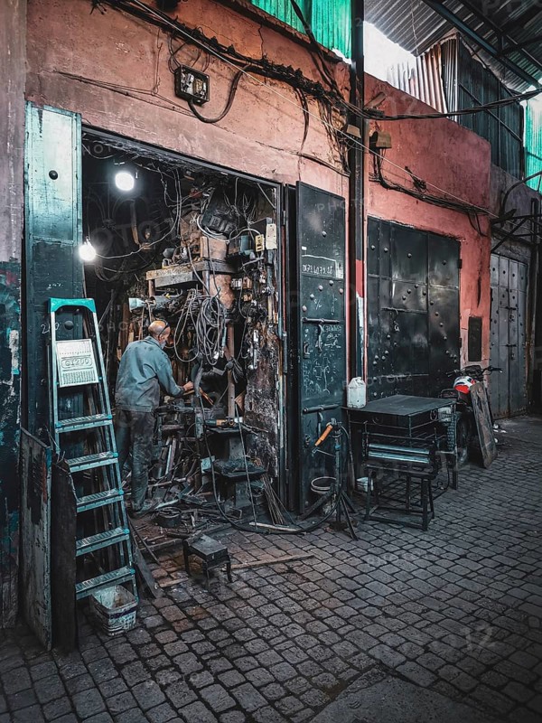 Small, dark workshop full of cables and metal in the Medina with craftsmen at work, atmospheric lighting, nostalgic atmosphere, Morocco